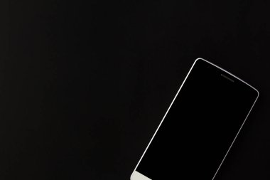 Beyaz telefon siyah bir arka planda yatıyor