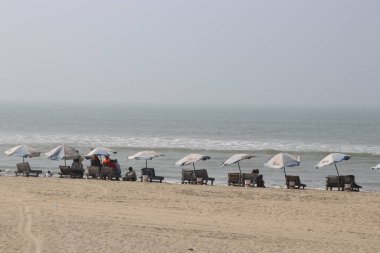 Mutlu insanlar güzel bir manzara görmek için deniz sahilinde otururlar. Seyahat ya da deniz tatili konsepti ve güzel bir manzaranın tadını çıkarmak.