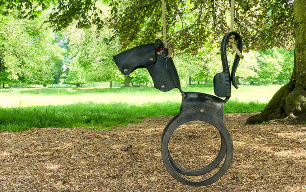 Recycled garden swing hanging from a tree over wood chippings. Re-modelled into the shape of a horse from an old car tyre. Well used but currently unoccupied. Countryside background. England