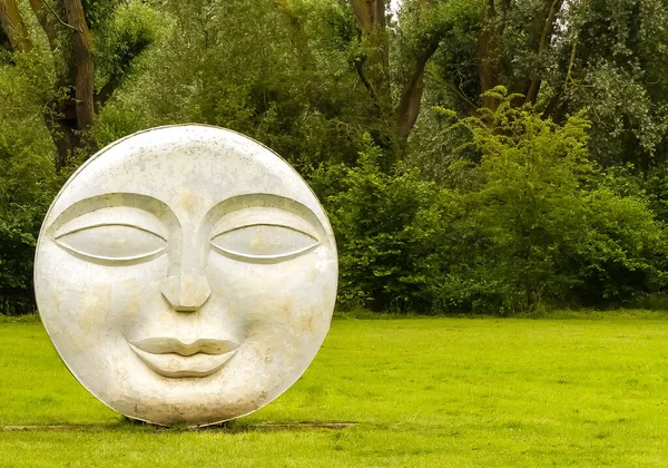 Frilford, Oxfordshire 'da. İngiltere - 30 Haziran 2020: Halka açık bir alanda gözü, burnu ve ağzı olan eskimiş beton yüzlü heykel. Kopyalamak için alanı olan soyut resmi düzenle.