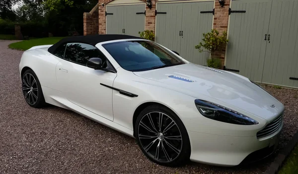 Stafford, Staffordshire. İngiltere - 8 Ağustos 2019: beyaz, boş, üstü açık Aston Martin DB9, çatısı açık, bir garajın dışında oturuyor. Peyzaj resmi.