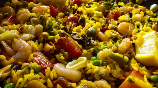 Kalamar, midye ve karides, taze domates, bezelye, pirinç ve limonlu ev yapımı deniz ürünleri paella 'sının renkli yakın çekimi. Doğal ışık alan manzara görüntüsü. Metin için boşluk. 