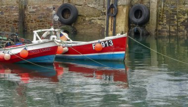 Mevagissey, Cornwall. İngiltere - 22 Eylül 2020: Kasaba limanı içinde demirlemiş renkli balıkçı tekneleri. Deniz duvarının arka planında yansıtıcı görüntü. Kopyalamak için boşluk.