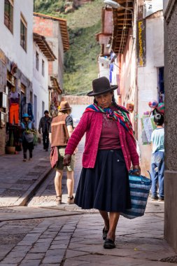 Pisac, Peru - 02.23.2020: Küçük bir kızla birlikte Perulu kadınlar, Pisac sokaklarında mal satıyorlar