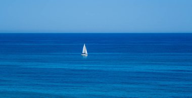 Yalnız beyaz bir yat açık denizde.