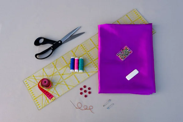 A set for cutting and sewing: silk fabric, threads, scissors, measuring ruler, meter, pins, buttons, chalk for marking