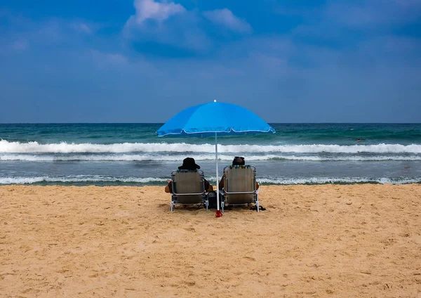 Casal em espreguiçadeiras relaxar em uma praia do mar — Fotografia de Stock