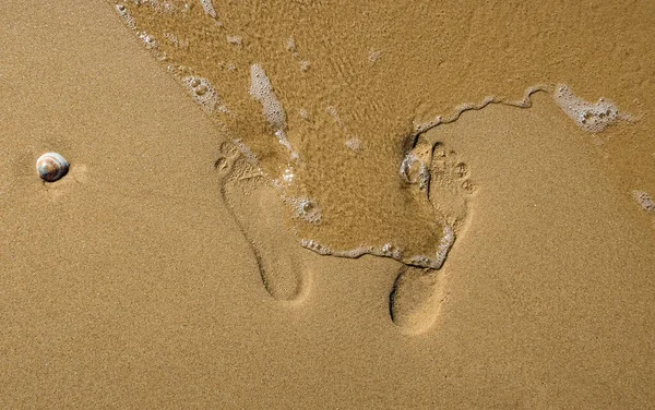 Das Meer spült die Fußspuren im Sand am Ufer weg Stockfoto