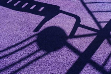 Mor zemindeki oyun alanı gölgeleri soyut geometrik desen oluşturuyor.