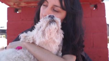 Bir kız tüylü köpeğine sarılıyor.
