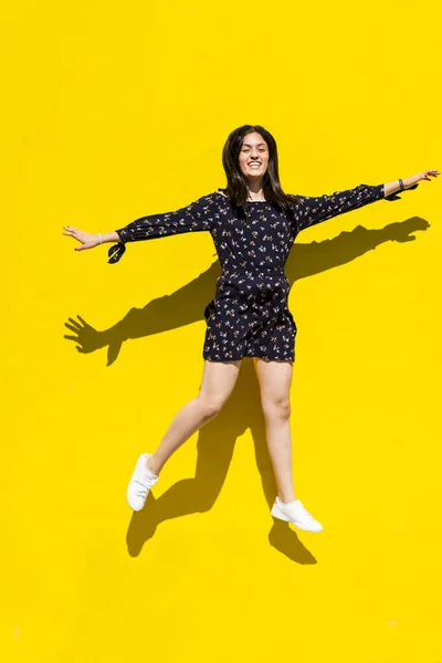 Urban women latin jumping over isolated yellow background and dancing