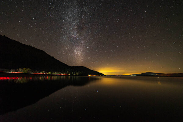 Bassenthwaite Lake in the lake district with the Milky Way and car lights trailing from the A66 on the lake