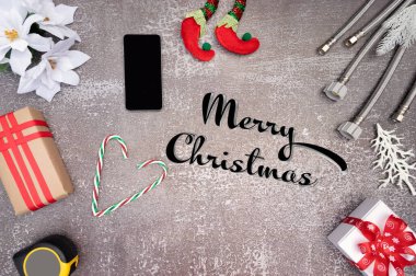 Cep telefonu, hediye kutuları ve arka planda inşaat aletleri olan Noel ve Yeni Yıl dekorasyonu. Tesisatçı Noel.