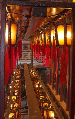 Geleneksel ahşap ve cam fenerler Hong Kong 'daki Man Mo Tapınağı' nın altında asılı kırmızı kağıtlara yazılı.