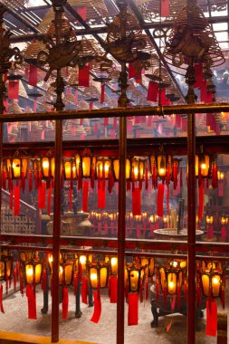 Geleneksel ahşap ve cam fenerlerin genel görünümü altında kırmızı kağıtlara yazılı olan Çin fenerleri ve Hong Kong Man Mo Tapınağı 'ndaki kırmızı tütsü spiralleri.