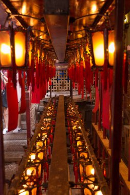 Geleneksel ahşap ve cam fenerler Hong Kong 'daki Man Mo Tapınağı' nın altında asılı kırmızı kağıtlara yazılı.