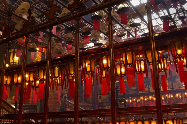 Geleneksel ahşap ve cam fenerlerin genel görünümü altında kırmızı kağıtlara yazılı olan Çin fenerleri ve Hong Kong Man Mo Tapınağı 'ndaki kırmızı tütsü spiralleri.