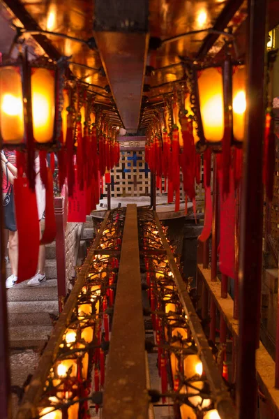 Geleneksel ahşap ve cam fenerler Hong Kong 'daki Man Mo Tapınağı' nın altında asılı kırmızı kağıtlara yazılı.