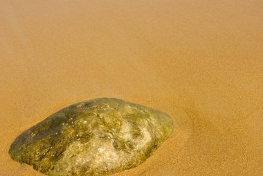 Kumsalda sarı kum dokusu ve bir taş..