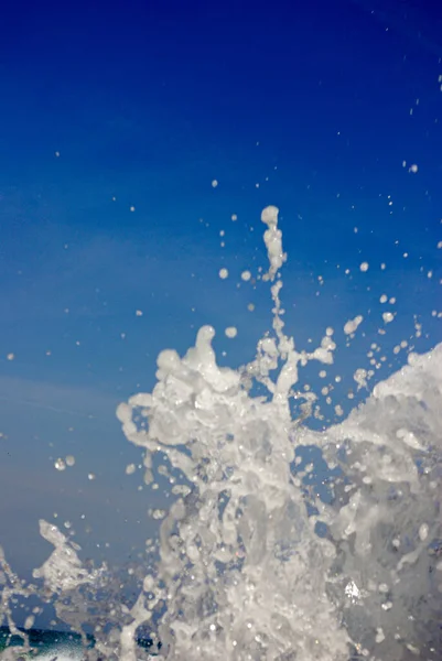 Su sıçrıyor. Kayalara vuran berrak deniz suyu. Kumsalın yukarısındaki mavi gökyüzü güneşli ve ferahlatıcı okyanus suyu damlaları. Deniz dalgaları kıyıda kırılır.