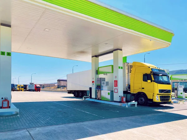 Ярко-желтый грузовик с холодильным полуприцепом на топливной остановке для заправки Лицензионные Стоковые Фото