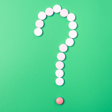 Yeşil arkaplanda soru işareti formunda birçok farklı hapı kapat.