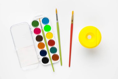 Renkli suluboya resimlerinin üst görünümü beyaz arka planda izole edilmiş ve fırçalar.