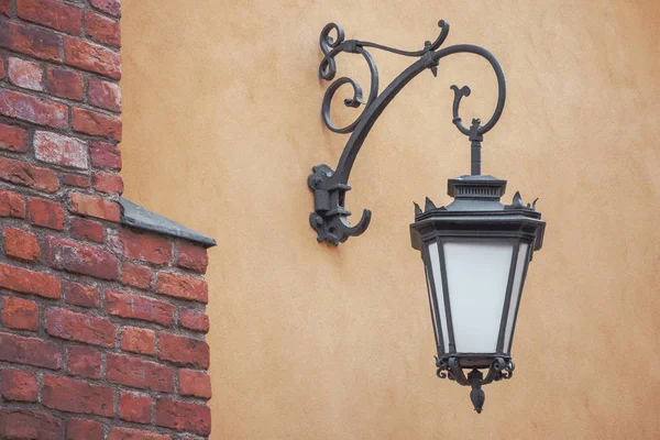 Old wrought-iron street lamp hanging on the wall of an urban house