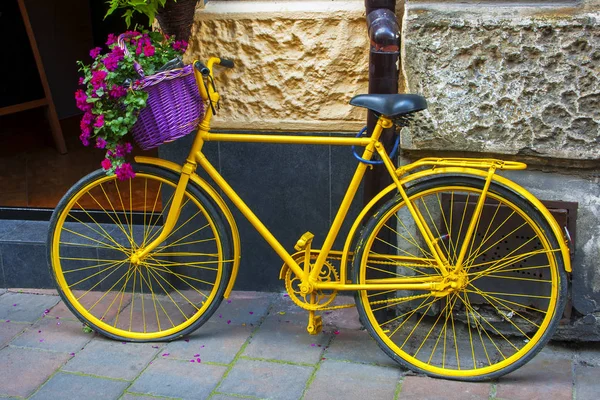 街の通りに古い黄色の自転車に掛かっているゼラニウムとバスケット — ストック写真