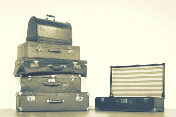 Old leather suitcases are stacked in an empty room.Toned photo