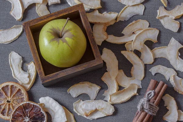 Apple in a wooden box, apple chips, dried orange and tied with cinnamon sticks are removed from above