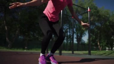 Formda bir kadın stadyumda burpee egzersizi yapıyor.