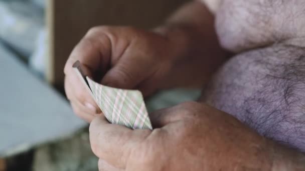 Närbild av händerna på en gammal man med bara överkroppen spelar kort i trädgården — Stockvideo