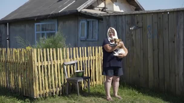 Plan général de grand-mère dans un foulard avec un chien dans les bras dans le jardin — Video