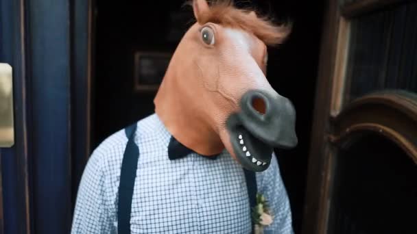 Homem com uma máscara de cavalo balança a cabeça na porta do restaurante no verão — Vídeo de Stock