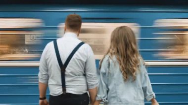 Aşıklar bir metroda duruyor ve önlerinden bir tren geçiyor.