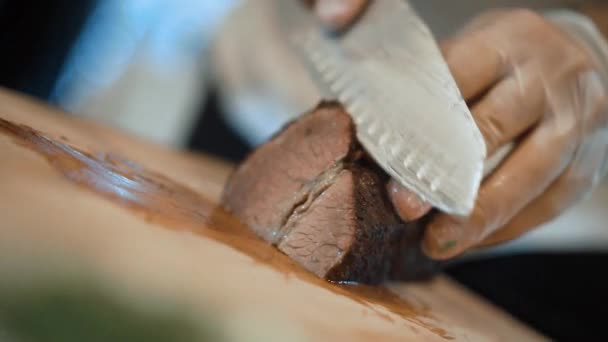 Câmera lenta um chef de luvas corta com faca um bife na tábua de madeira — Vídeo de Stock