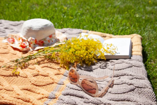 Strohhut Gelbe Wildblumen Aufgeschlagenes Buch Sonnenbrille Auf Einer Gestrickten Beige — Stockfoto