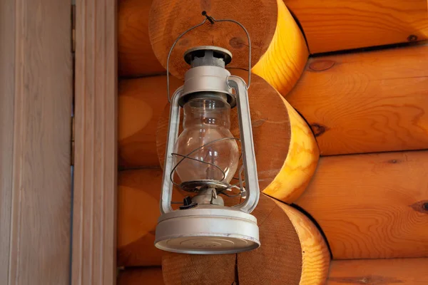 A kerosene or gas lamp hangs on the wall of a wooden log house — Stock Photo, Image