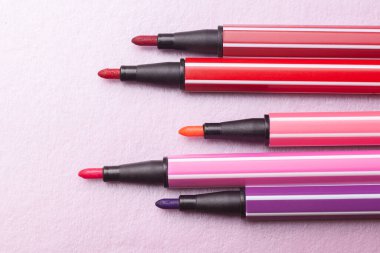 Beş açık işaret ya da pembe, mor, pembe renkli kalem gümüş, gri arka plan, izole edilmiş maket gibi uzanır.