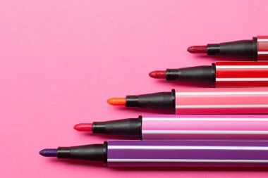 Beş açık işaret ya da pembe, mor, pembe renkli kalem pembe arka plandaki basamaklar gibi uzanıyor, izole edilmiş maket gibi.