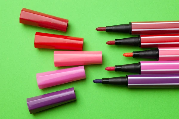 Cinco marcadores abiertos o bolígrafos de color rosa, púrpura, rosa se encuentran como pasos sobre un fondo verde, simulacro aislado hasta —  Fotos de Stock