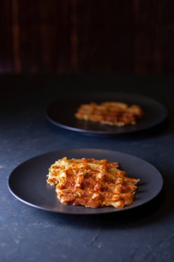 Kızarmış Viyana kabağı waffle 'ı iki siyah tabak üzerinde koyu beton arka planda, minimalizm