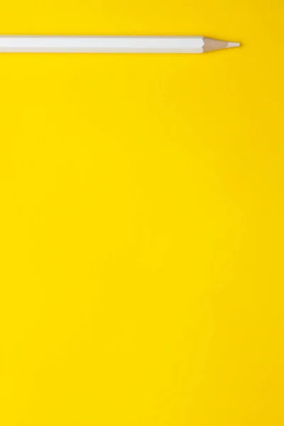 Lápiz de madera afilado blanco vertical sobre un fondo amarillo brillante, aislado, espacio de copia, se burlan de — Foto de Stock