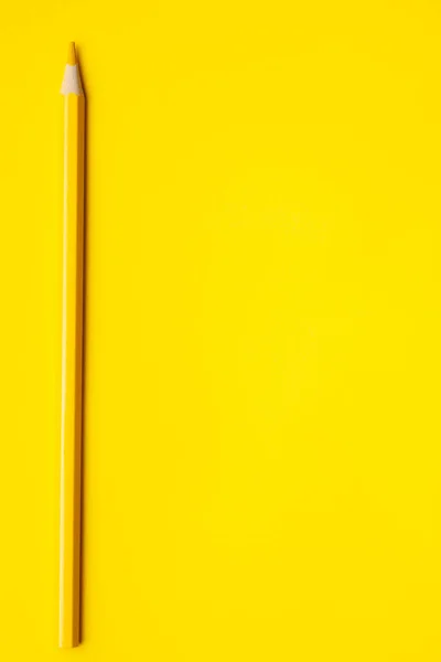 Lápiz de madera afilado amarillo vertical sobre un fondo amarillo brillante, aislado, espacio de copia, se burlan de — Foto de Stock