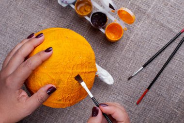 Cadılar Bayramı dekorasyonu, boya çizimi, çuval bezi arkaplanı için kağıt hamurundan balkabağı yaratma süreci