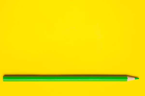 Crayon en bois pointu vert horizontal sur un fond jaune vif, isolé, espace de copie, maquette — Photo