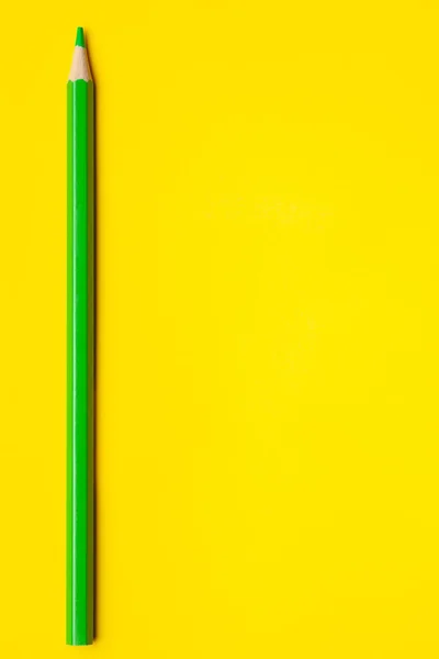 Vertical green sharp wooden pencil on a bright yellow background, isolated, copy space, mock up — Stock Photo, Image