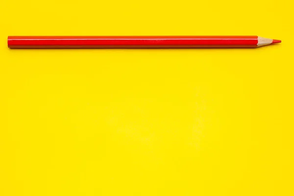 Горизонтальний червоний гострий дерев'яний олівець на яскраво-жовтому фоні, ізольований, копіювати простір, сміється — стокове фото