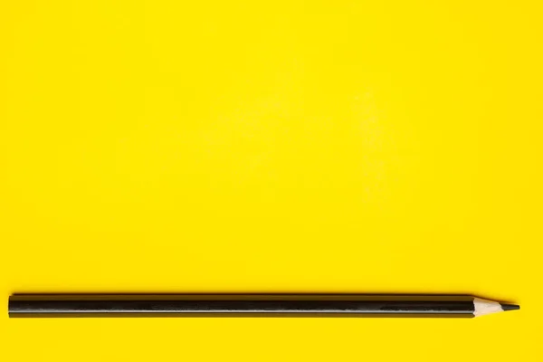 Горизонтальный черный острый деревянный карандаш на ярко-желтом фоне, изолированный, копировальное пространство, макет — стоковое фото